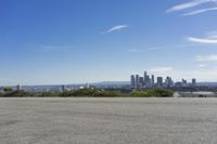 an adult woman with sunglasses riding a motorcycle and looking at a city skyline from a viewpoint