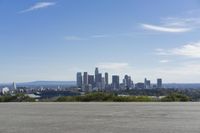 an adult woman with sunglasses riding a motorcycle and looking at a city skyline from a viewpoint