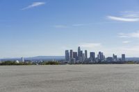 an adult woman with sunglasses riding a motorcycle and looking at a city skyline from a viewpoint