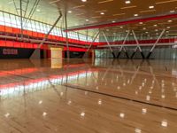 an indoor gymnasium with wood floors and lots of lights on it with an orange wall