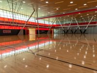 an indoor gymnasium with wood floors and lots of lights on it with an orange wall