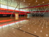 an indoor gymnasium with wood floors and lots of lights on it with an orange wall