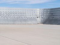 a man wearing a white suit standing in front of a blue building on a tarmac