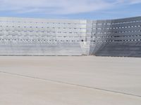 a man wearing a white suit standing in front of a blue building on a tarmac