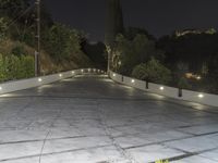 a concrete road lined with lights over the curb of an apartment building at night,