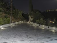 a concrete road lined with lights over the curb of an apartment building at night,