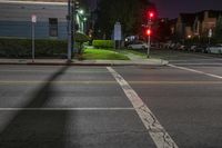 an intersection with parked cars on either side at night time, street lights on one of them