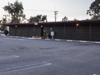 a building with a metal fence and parking lot with several cars parked in the front