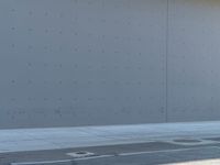 a person walking towards an airplane next to a building or hangar with windows to let in light