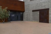 a brown concrete building with an entry and garage door with trees in front of it