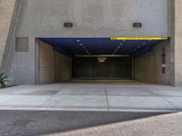 an empty building has a parking garage with yellow lights and a blue cover over it