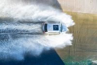 an suv drives through the water on its way to shore with large waves coming from behind