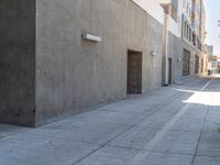 a green fire hydrant stands next to a wall and concrete block wall near a sidewalk