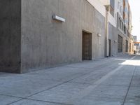 a green fire hydrant stands next to a wall and concrete block wall near a sidewalk