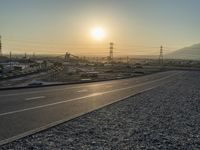 sunset over an intersection in an empty lot with no vehicles on it but the lights on