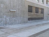 a man walking on sidewalk in front of a building while holding a blue bag and smoking