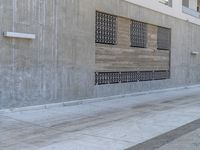 a man walking on sidewalk in front of a building while holding a blue bag and smoking