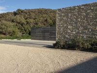 a boy on a skateboard in the middle of an empty road near a stone wall