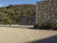 a boy on a skateboard in the middle of an empty road near a stone wall