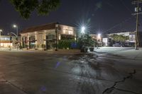 night photo of an empty city street, with a small shop in the background and some tree lights