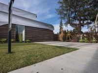 the building is surrounded by trees in the front yard and has plants, grass, and trees growing on it