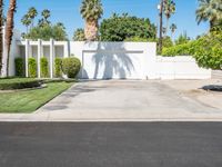 the driveway of the house is blocked off by a fence and palm trees near the entrance