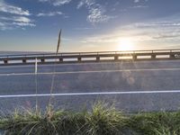 a highway next to some water and some grass with the sun shining above it and a sea