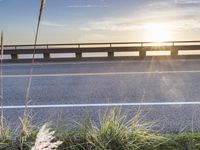 a highway next to some water and some grass with the sun shining above it and a sea