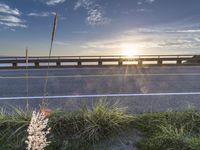 a highway next to some water and some grass with the sun shining above it and a sea