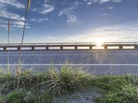 a highway next to some water and some grass with the sun shining above it and a sea