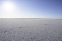 the sun shines brightly on an icy beach near land and water in the distance