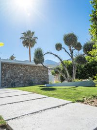 a large house with a driveway in front of it and a small stone wall and trees