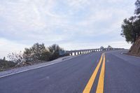 a curved road winds through a scenic area under a cloudy sky at dusk with traffic