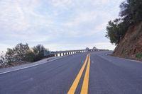 a curved road winds through a scenic area under a cloudy sky at dusk with traffic