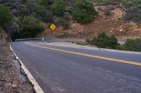 a hill side curve next to a road with two yellow lines in the middle of it