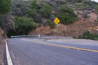 a hill side curve next to a road with two yellow lines in the middle of it