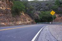 a hill side curve next to a road with two yellow lines in the middle of it