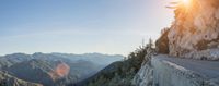 two people on bicycles are going over a mountain cliff and looking at the sunset over a valley