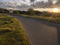 a sun setting over a golf course and a house with a lot of grass in front