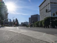 the sun is shining on an empty street in a city area and people are crosswalking