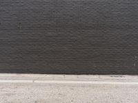 a black brick wall with no visible bricks in it and a street sign attached to the curb