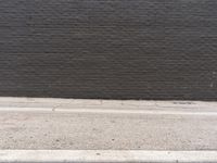 a black brick wall with no visible bricks in it and a street sign attached to the curb