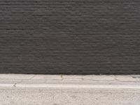 a black brick wall with no visible bricks in it and a street sign attached to the curb