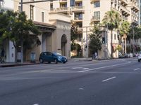 two people are crossing the street with traffic light on in front of him, where the buildings are tan and one is white