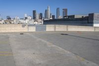 an empty parking lot with city skyline in the background on a sunny day with no people or cars