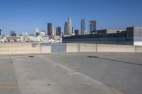 an empty parking lot with city skyline in the background on a sunny day with no people or cars