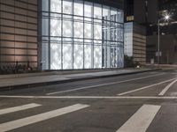 a building has a glass front in a city street, with greenery in front