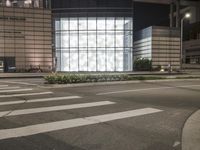 a building has a glass front in a city street, with greenery in front