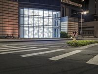 a building has a glass front in a city street, with greenery in front