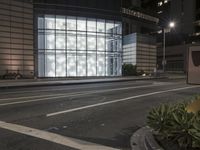 a building has a glass front in a city street, with greenery in front